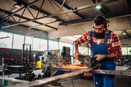 Hardworking man grinding a metal construction with great dedication.