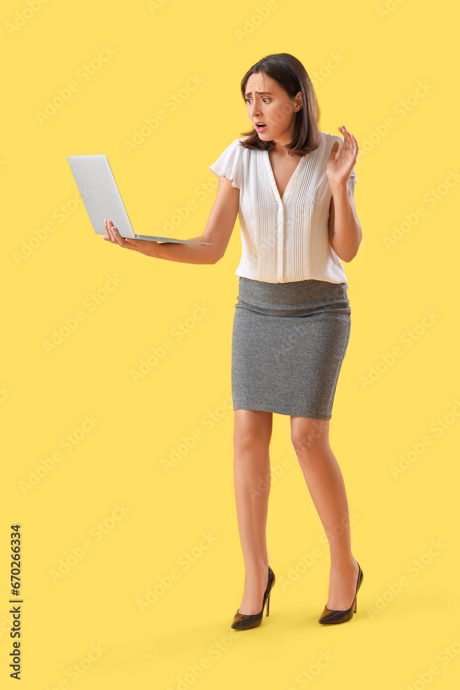 Young afraid woman with laptop on yellow background Young afraid woman with laptop on yellow background