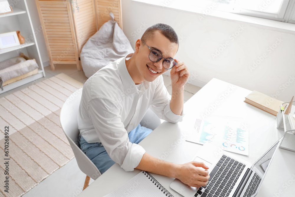 Handsome young businessman working with laptop at workplace in office
