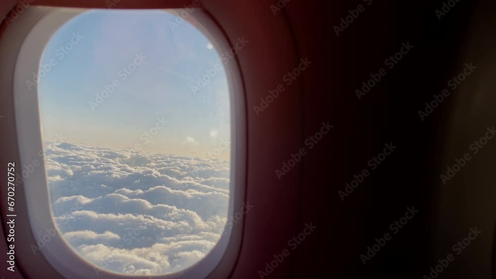 Passenger opening up aircraft porthole with bright morning clouds picturesque cloudscape view litted with sun rays and everything. 4K People traveling, wake up and transportation concept footage.