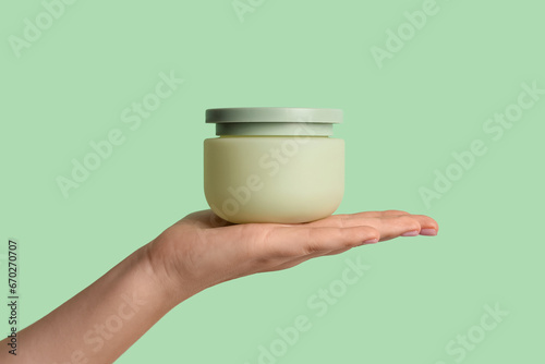 Female hand with jar of cosmetic product on color background, closeup