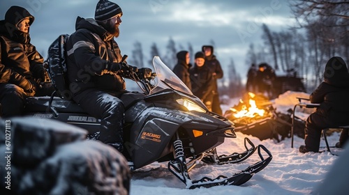 Snowmobilers gathered around a warming campfire photo
