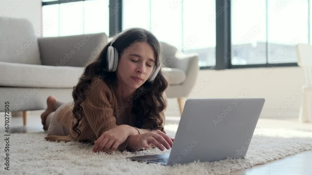 Bored Caucasian woman lies on the floor, letting out a yawn while laptop sits beside her. Her face reflects a sense of ennui, and the room is filled with a quiet stillness. Bored Caucasian woman lies on the floor, letting out a yawn while laptop sits beside her. Her face reflects a sense of ennui, and the room is filled with a quiet stillness.