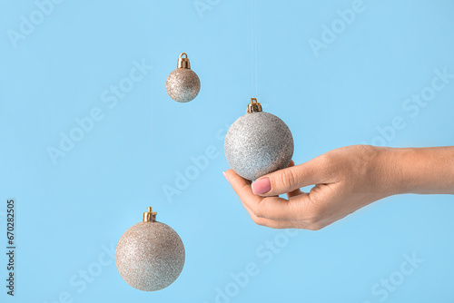 Female hand with Christmas balls on blue background