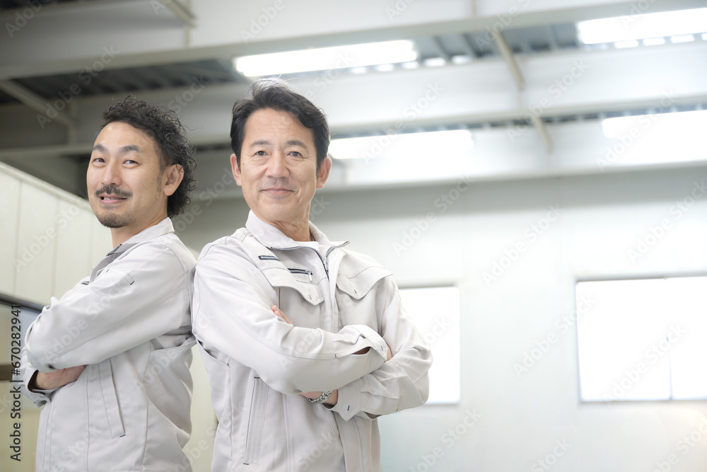 倉庫で腕組をする笑顔の作業員2人 製造業や流通 右にコピースペースあり 倉庫で腕組をする笑顔の作業員2人 製造業や流通 右にコピースペースあり