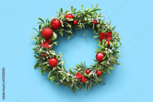 Christmas mistletoe wreath with balls and bows on blue background