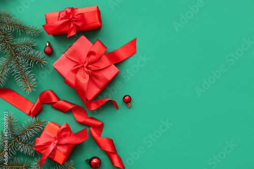Red gift boxes with Christmas tree branches and balls on green background