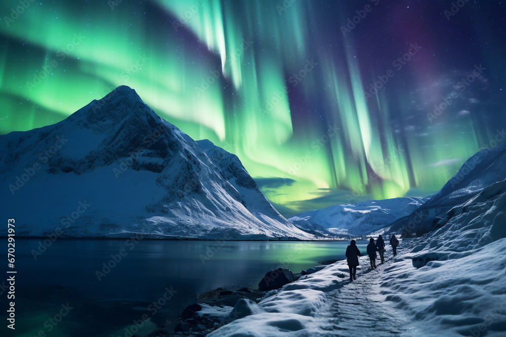 A close up of a group of tourist mountaineers and their guide are hiking to a rock in front of a mountain lake with thick coats on a in snow covered mountain hill with northern lights with trails of f