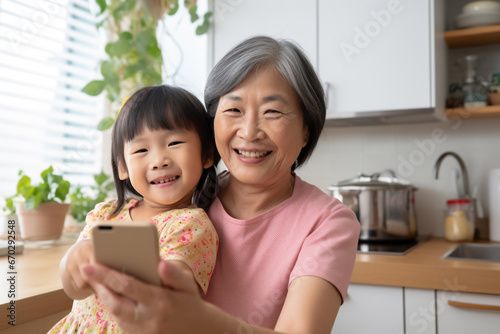 A senior asian woman is is making a selfie while smiling with a telephone in a modern living room a low tech social media woman