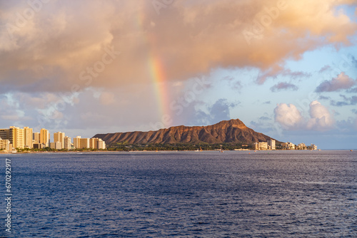 At sunset, a rainbow appears over diamond head in Oahu, Hawaii.