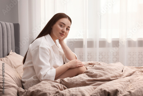 Beautiful woman sitting on bed at home, space for text. Lazy morning
