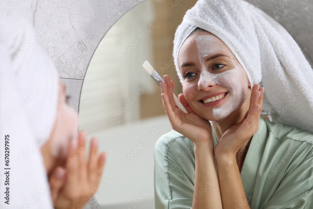 Woman with face mask in front of mirror indoors. Spa treatments Woman with face mask in front of mirror indoors. Spa treatments