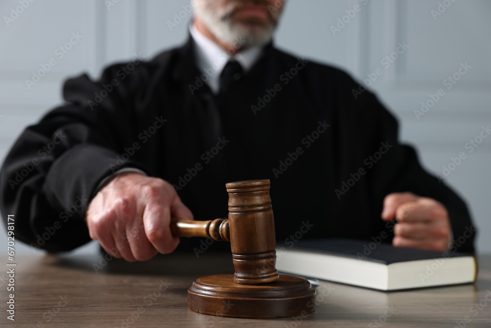 Judge with gavel and book sitting at wooden table indoors, closeup Judge with gavel and book sitting at wooden table indoors, closeup