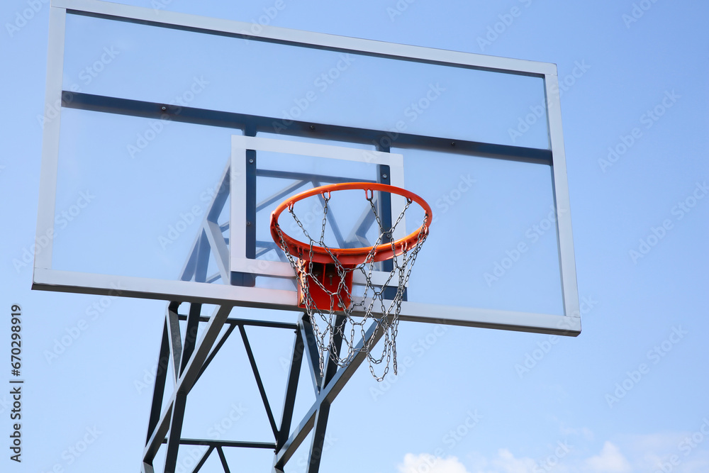 Basketball backboard with hoop outdoors against blue sky