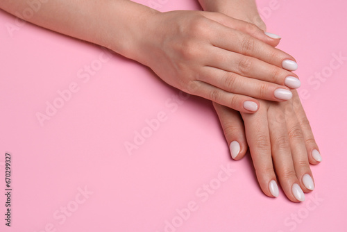 Woman showing her manicured hands with white nail polish on pink background  closeup. Space for text