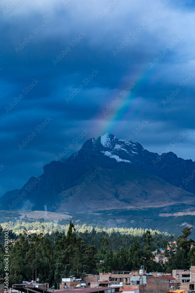 Magnificent rainbow over the mountain peaks covered with snow at sunset in the Peruvian city of Huaraz.