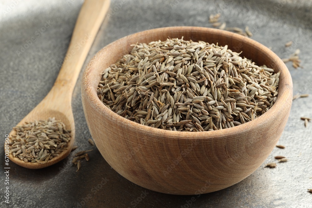 Bowl of caraway seeds and spoon on grey table, closeup - obrazy, fototapety, plakaty 