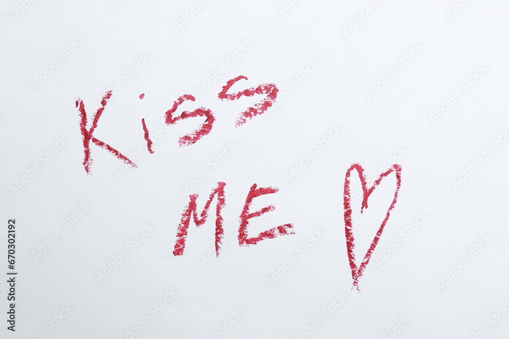Red heart and phrase Kiss Me written with lipstick on white background, above view