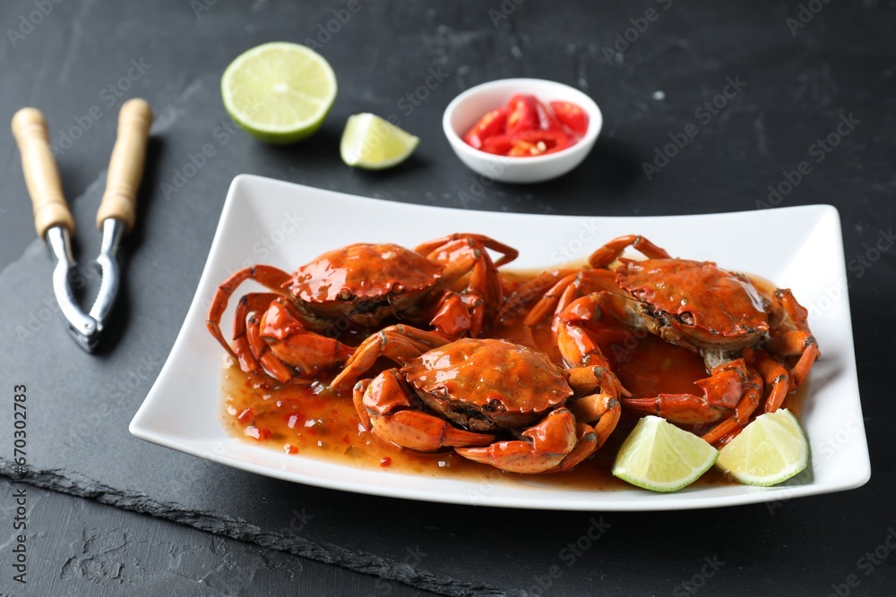 Delicious boiled crabs with sauce and lime on black textured table