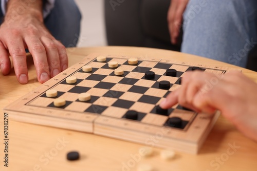 People playing checkers at wooden table, closeup © New Africa