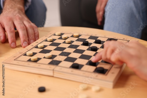 People playing checkers at wooden table, closeup