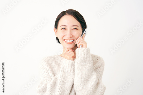スマートフォンで通話しながら想像する女性 白背景