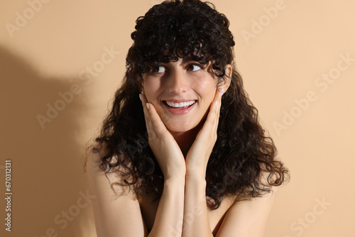 Portrait of beautiful young woman in sunlight on beige background