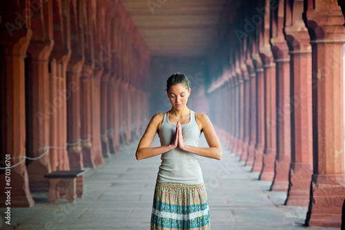 A beautiful young girl of European appearance meditates in an Indian ashram with her hands folded in namaste.