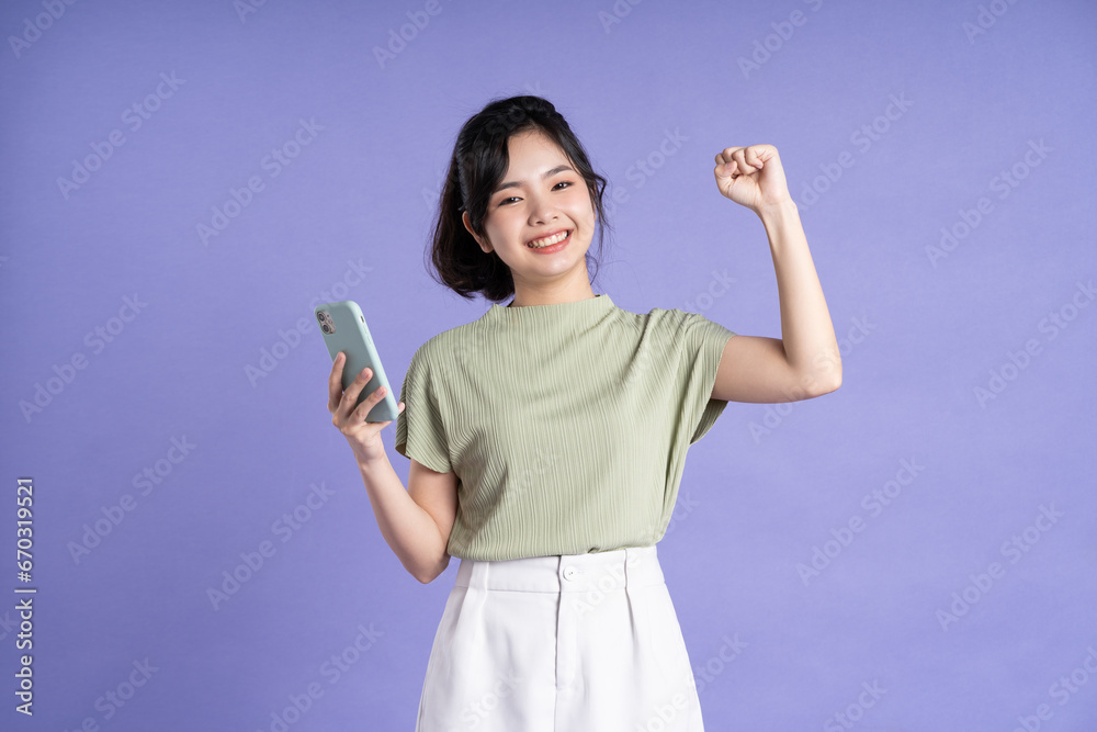 Portrait of beautiful asian woman using smartphone on purple background Portrait of beautiful asian woman using smartphone on purple background