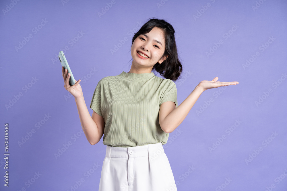 Portrait of beautiful asian woman using smartphone on purple background