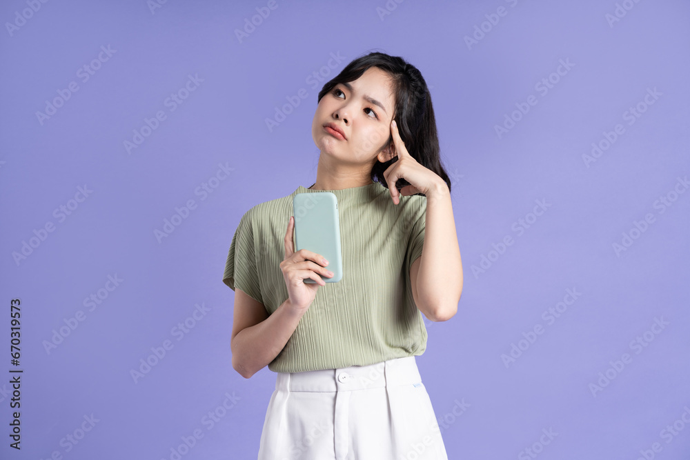 Portrait of beautiful asian woman using smartphone on purple background Portrait of beautiful asian woman using smartphone on purple background