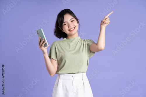 Portrait of beautiful asian woman using smartphone on purple background