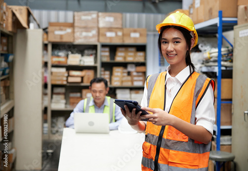 portrait worker working on tablet beside cardboard box on shelf in warehouse storage