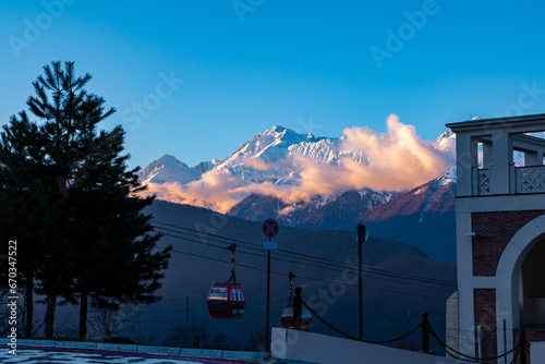 The cabin of the aerial lift against the backdrop of picturesque mountains covered with snow in the evening photo