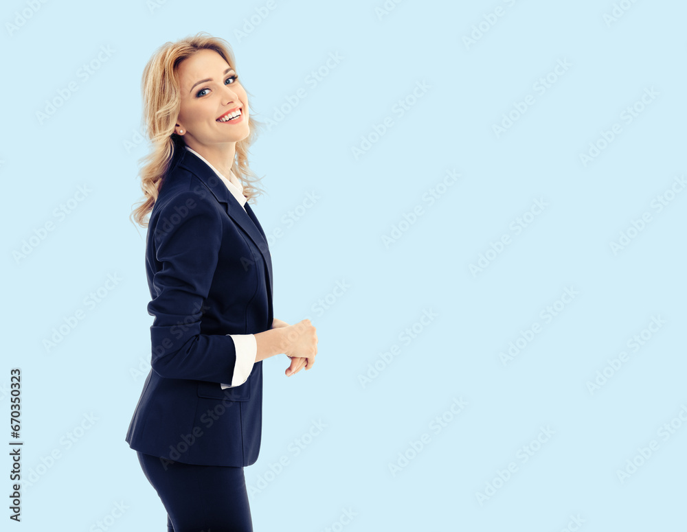 Portrait of happy smiling young businesswoman in dark confident suit, isolated on bright sky blue color background. Business studio concept. Copy space text area. Portrait of happy smiling young businesswoman in dark confident suit, isolated on bright sky blue color background. Business studio concept. Copy space text area.