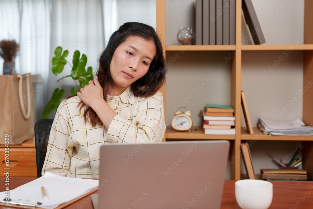 Young Asian woman, office worker, sitting in front laptop computer, at table in home office room, woman feeling bored when body is tired step away from desk, move body twist body relieve aches pains. Young Asian woman, office worker, sitting in front laptop computer, at table in home office room, woman feeling bored when body is tired step away from desk, move body twist body relieve aches pains.