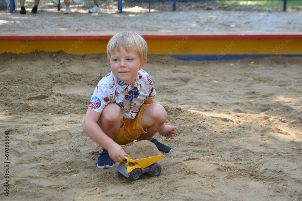 Cute toddler boyl playing in sand on outdoor playground. Cute toddler boyl playing in sand on outdoor playground.