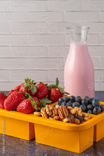 Lunchbox with fruits and granola and a glass of yogurt