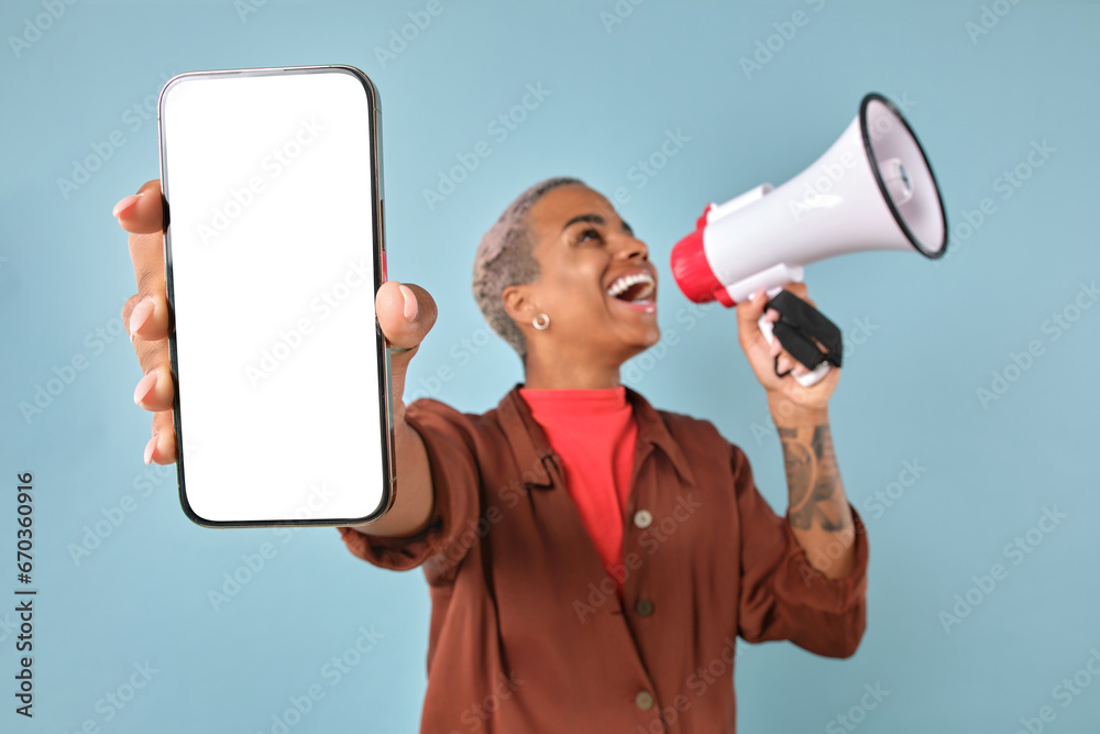 Young cheerful African American woman with megaphone and phone happily announces release of new model of mobile gadget sold at bargain price stands on plain turquoise background. White screen Young cheerful African American woman with megaphone and phone happily announces release of new model of mobile gadget sold at bargain price stands on plain turquoise background. White screen