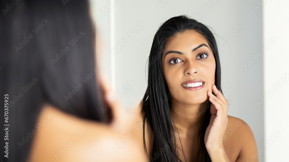Woman in front of bathroom mirror touching face Woman in front of bathroom mirror touching face