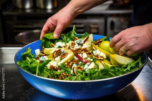 chefs hand tossing pear and blue cheese salad in a large salad bowl photo