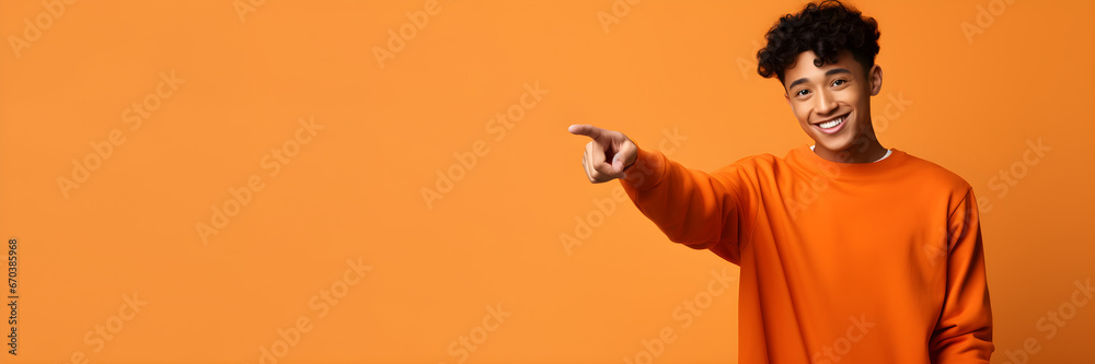 Happy funny African American teen guy pointing fingers to one side advertising new promo offer. Smiling black student model showing presenting ads standing isolated orange background with copy space Happy funny African American teen guy pointing fingers to one side advertising new promo offer. Smiling black student model showing presenting ads standing isolated orange background with copy space
