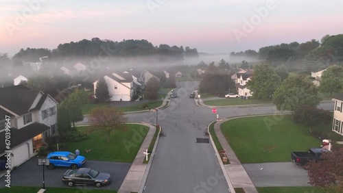 Low fog covers American neighborhood during sunrise. Aerial rising shot of townhouses and homes in surburbs. photo