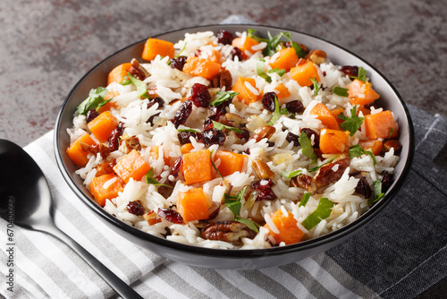 Fragrant rice with sweet potatoes, pecans, onions and dried cranberries close-up in a bowl on the table. Horizontal