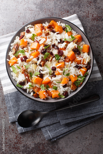 Basmati rice with sweet potato, nuts, pecans, onions and dried cranberries close-up in a bowl on the table. Vertical top view from above