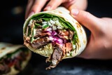 hand squeezing lime onto a filled shawarma wrap