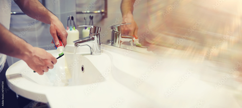 Tooth brush and paste with mirror background in the bathroom. Close up of toothpaste and toothbrush. Hands squeezing whitening paste on brush, taking care about mouth hygiene.