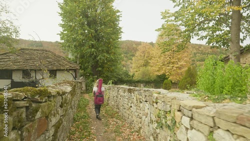 Happy young woman musician explores walled village lane Autumn scene photo