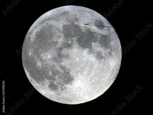 full moon in October 2023, Hunter's Moon, with silhouette of airplane passing by