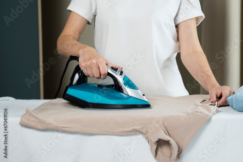Close up of unrecognizable young woman ironing clothes at home, simple lifestyle and household chores concept. 